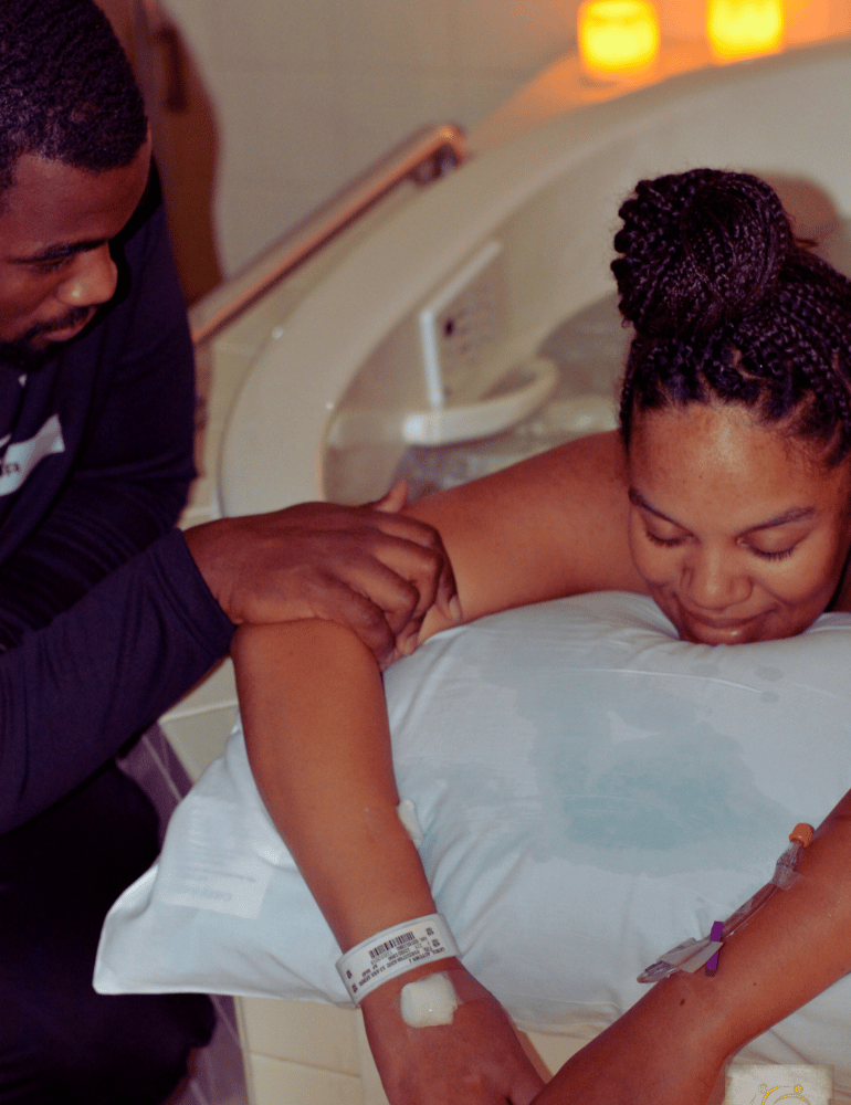Woman in birthing tub with a man comforting her.