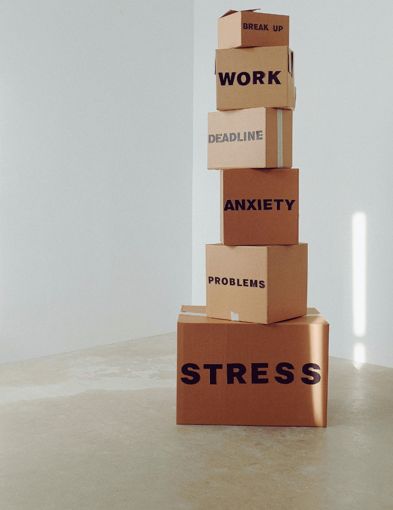 Stack of cardboard boxes labeled with stressors on a light background