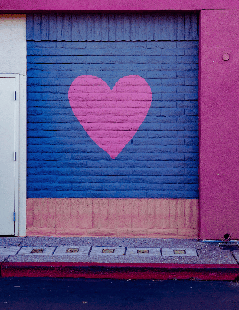 Pink heart on a blue brick wall with pink and purple sides.