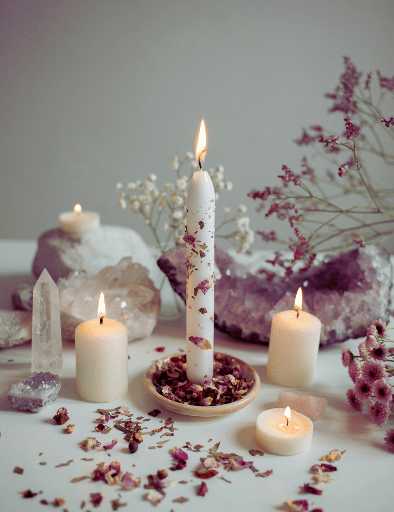 Candles, crystals, and flowers on a table with a neutral background