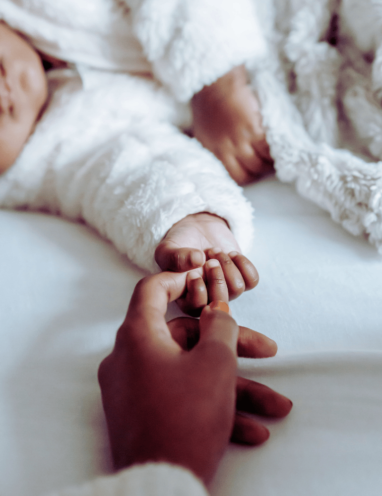 Close-up of a hand holding a child's hand, with a soft focus on the background.