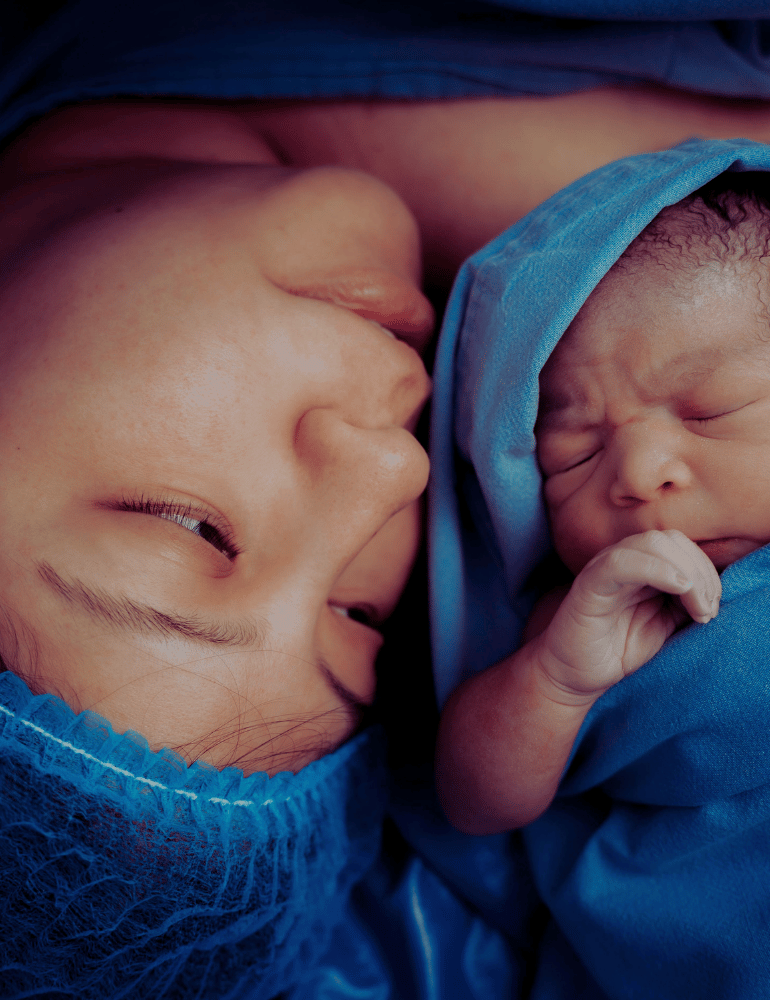 Mother sees newborn baby wrapped in blue cloth, close together.