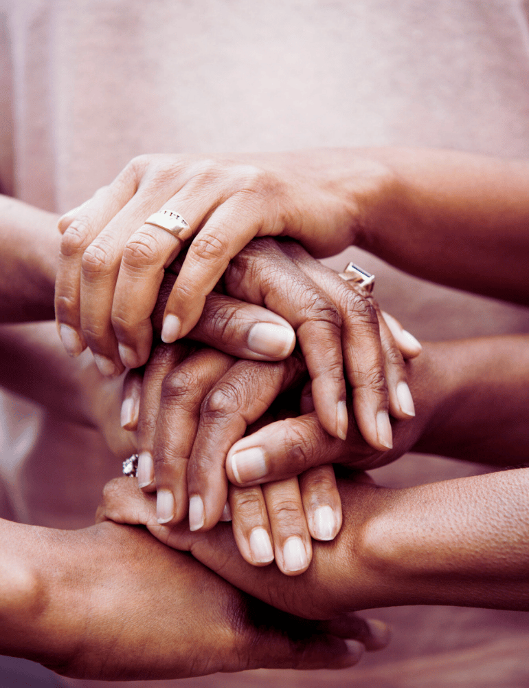 Four hands of different skin tones stacked together on a blurred background